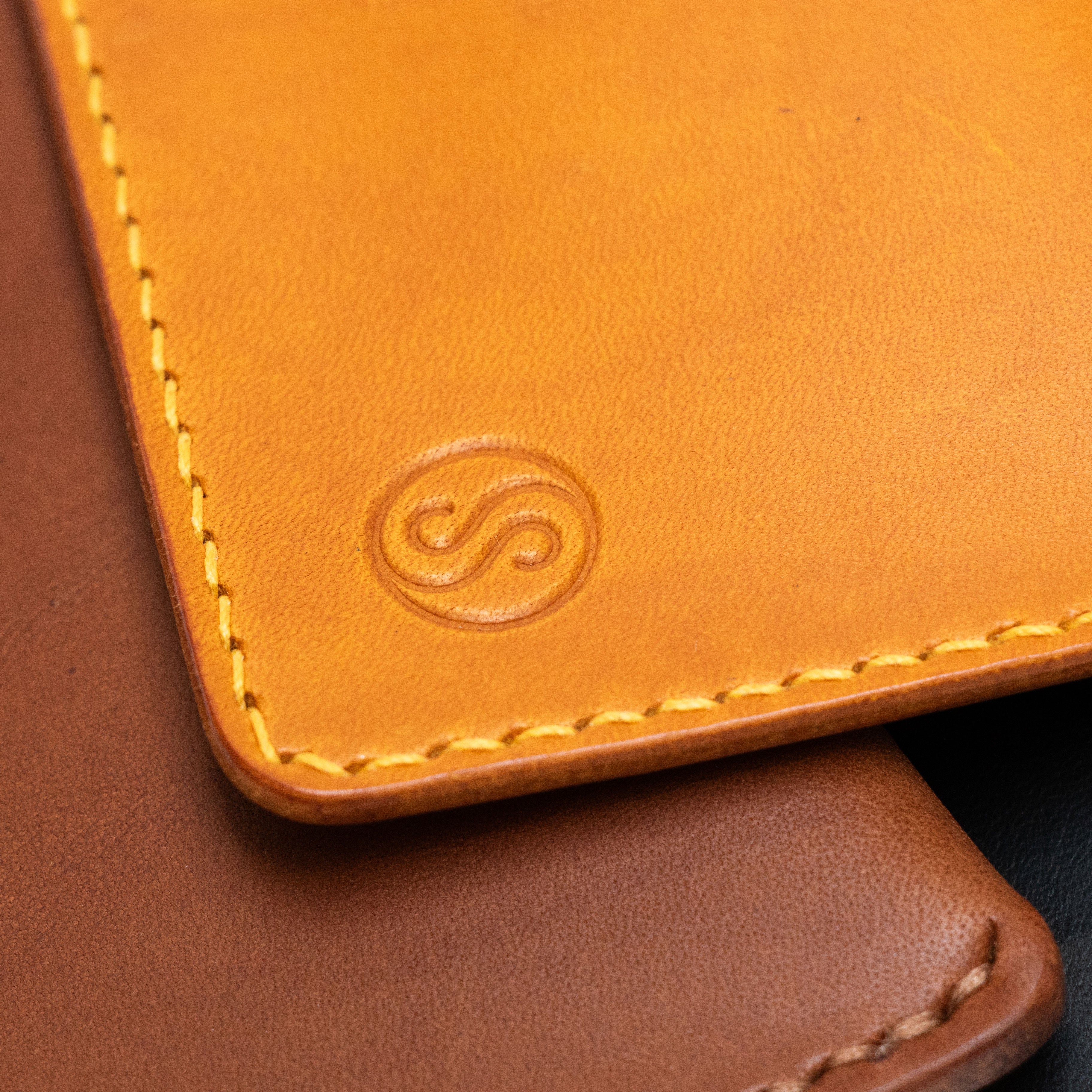 Close-up of a yellow leather wallet with visible stitching and brand logo.
