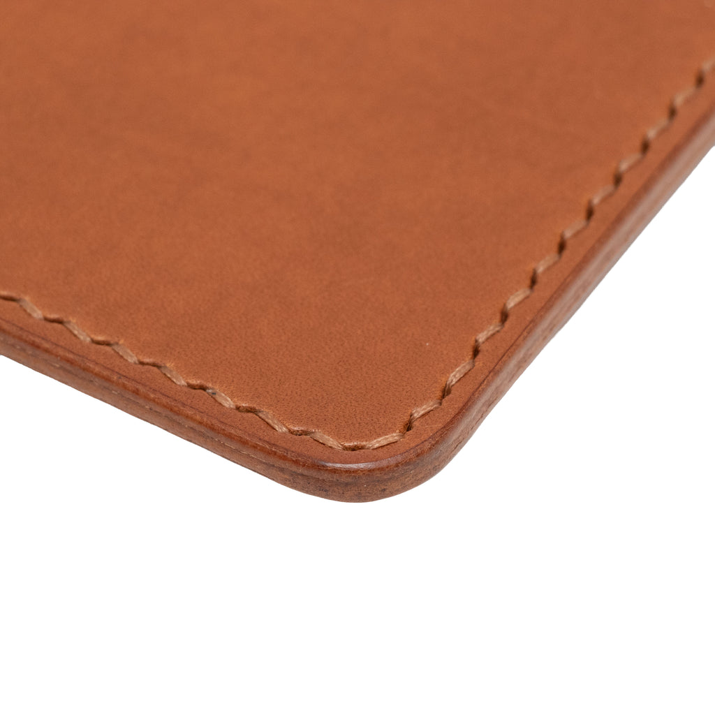 Close-up of a brown leather passport holder with visible stitching on a white background
