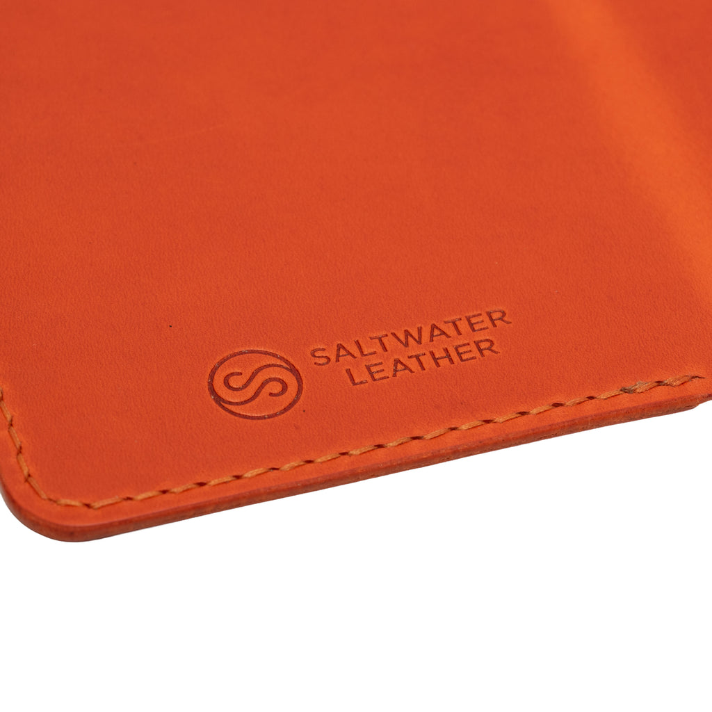Close-up of an orange leather product with Saltwater Leather branding.