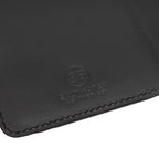 Close-up of a black leather passport holder with Saltwater Leather branding.