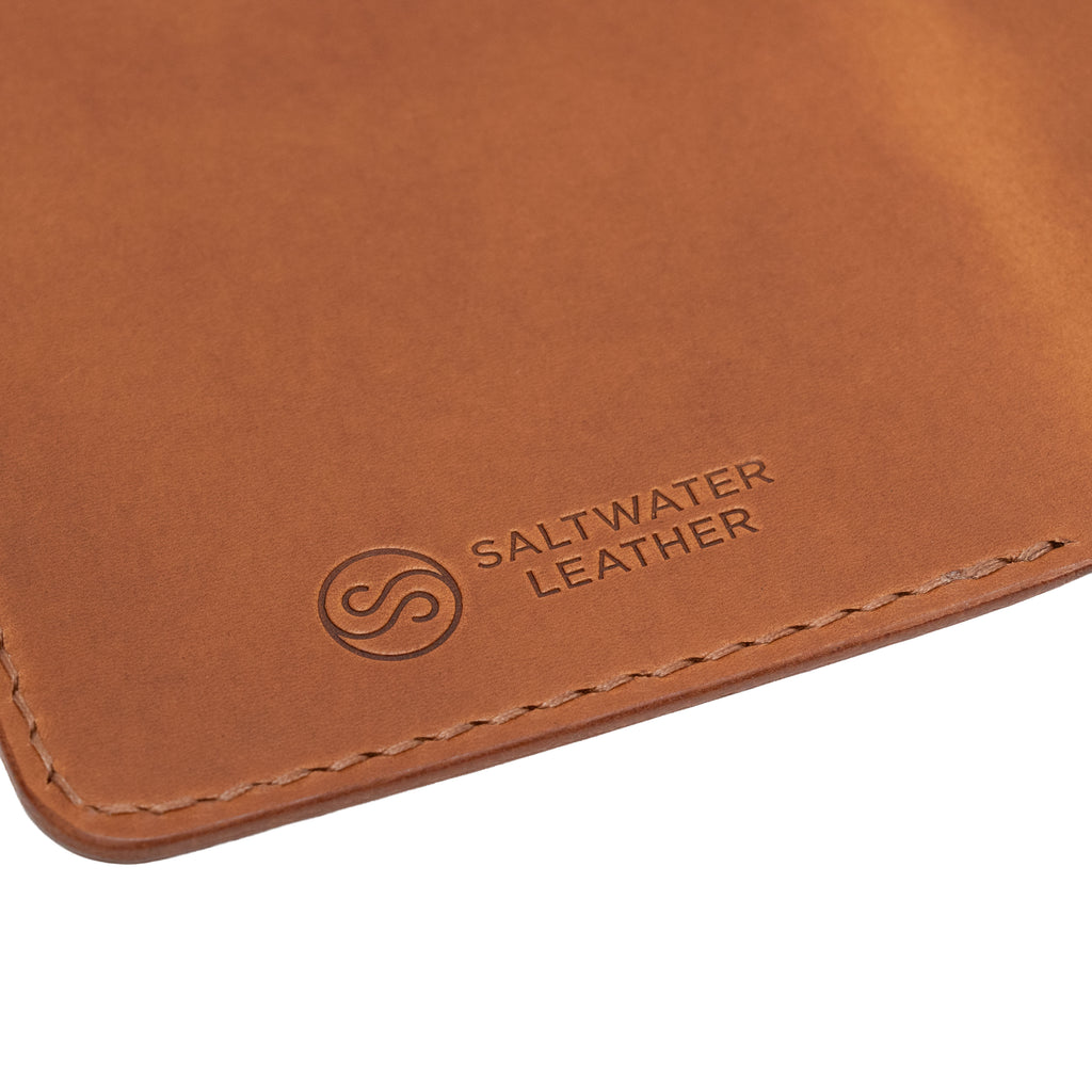 Close-up of a brown leather passport holder with Saltwater Leather branding.