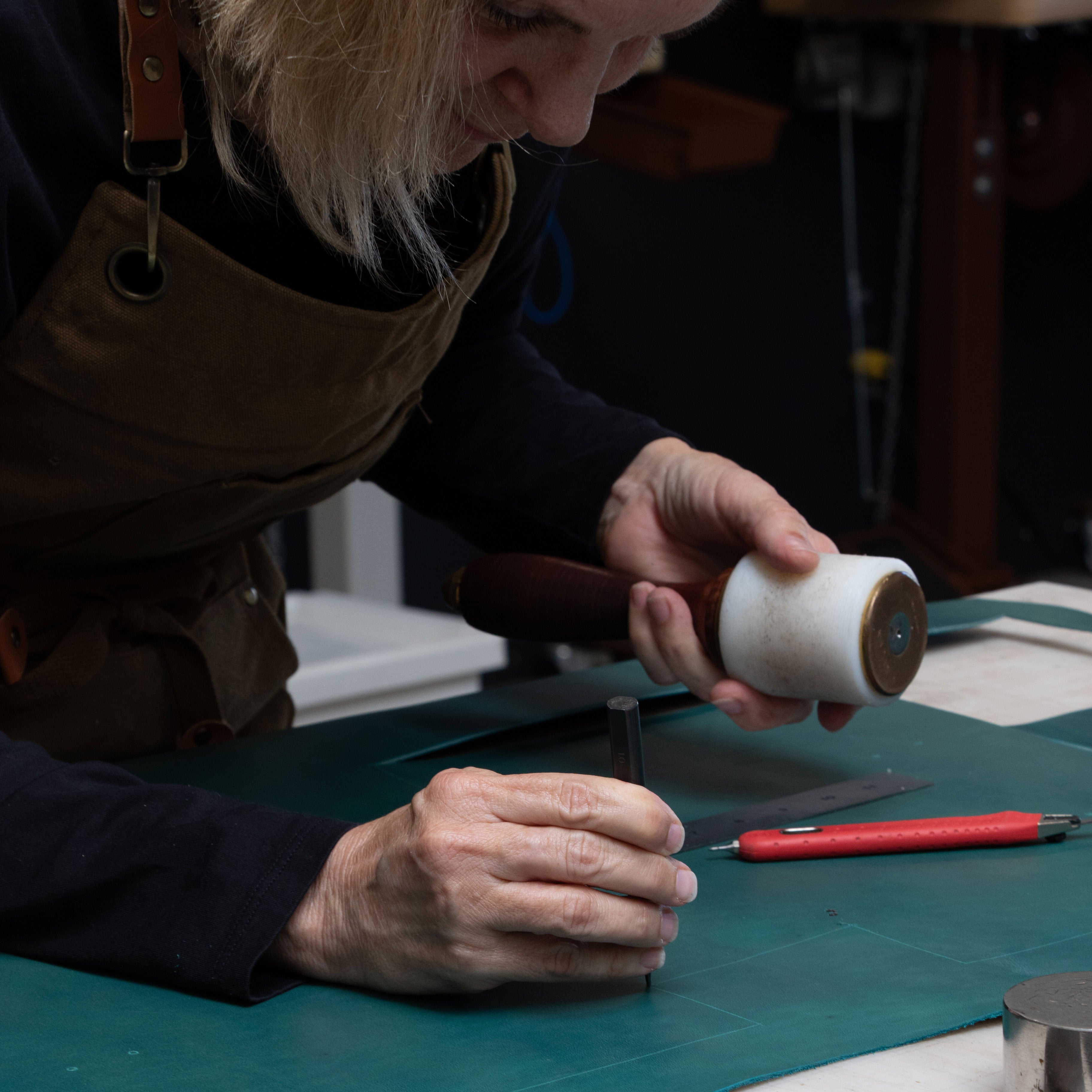 Person working with a leather working tool on a blue leather