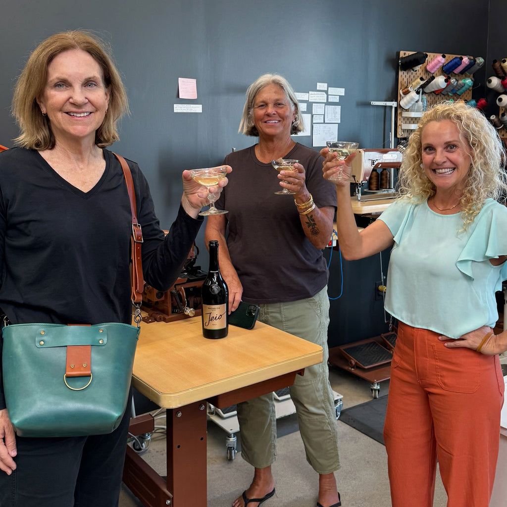 Three women toasting with drinks in a casual indoor setting
