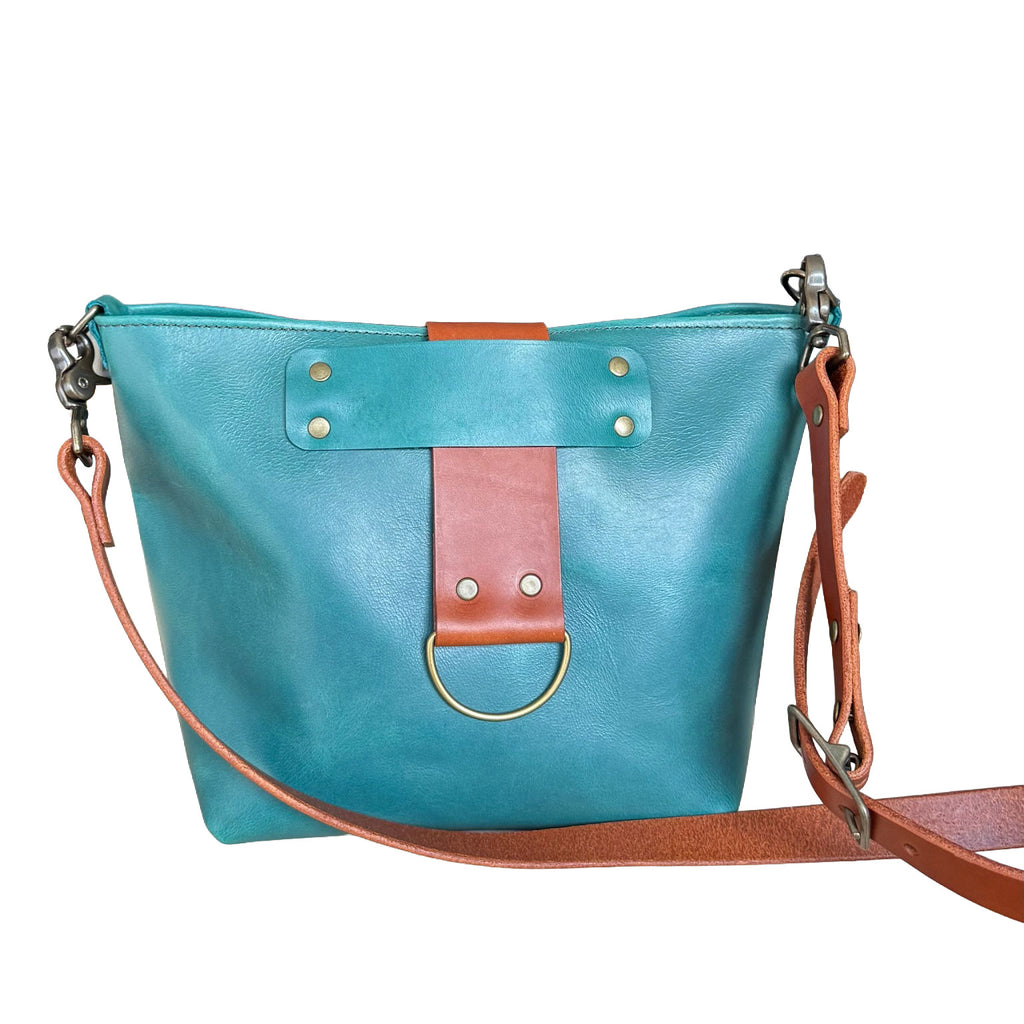 Turquoise handbag with brown leather accents on a white background