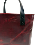 Red leather tote bag with black handle on a white background