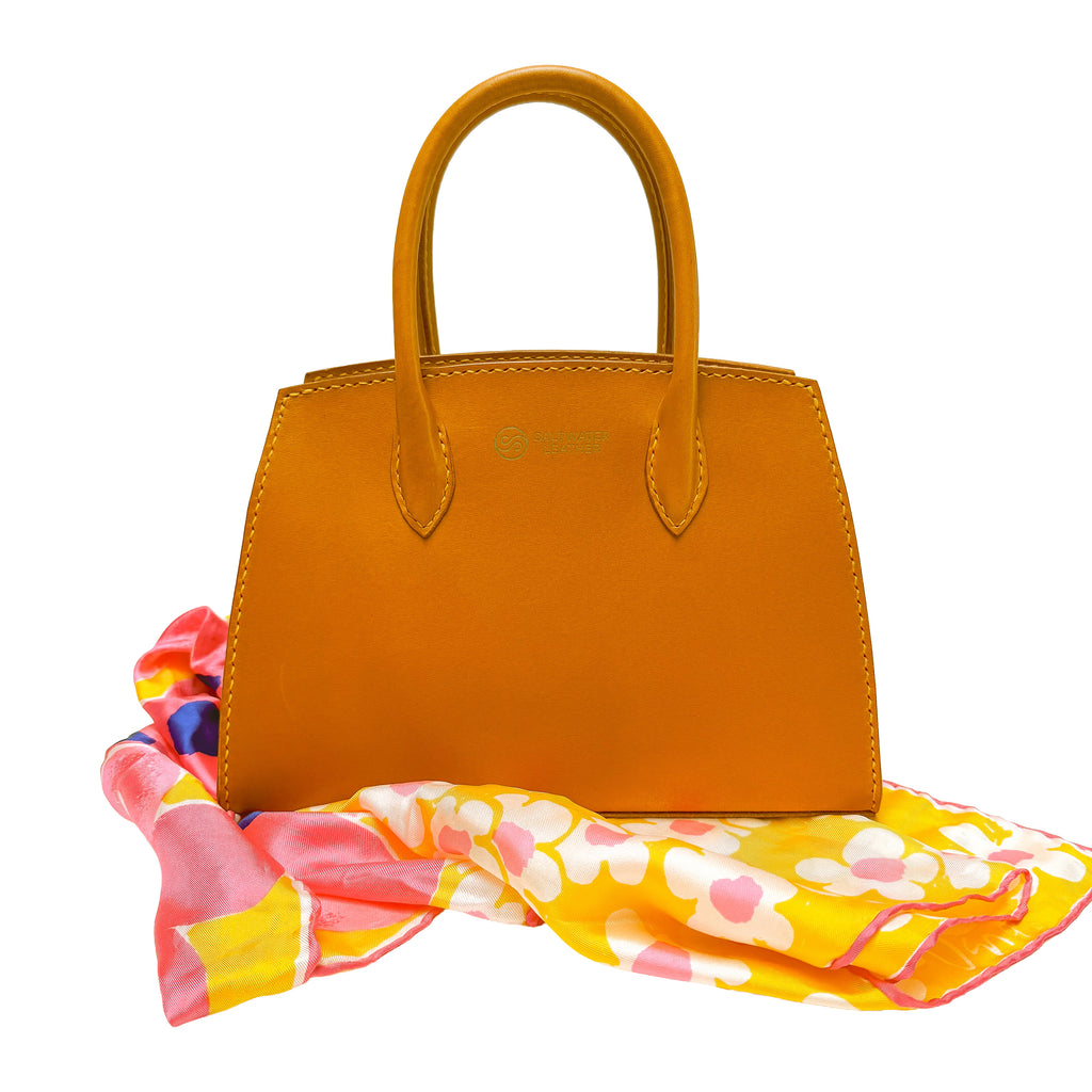 Yellow handbag with a colorful floral scarf on a white background