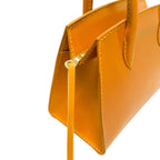 Close-up of a mustard yellow handbag with a visible brand logo on a white background