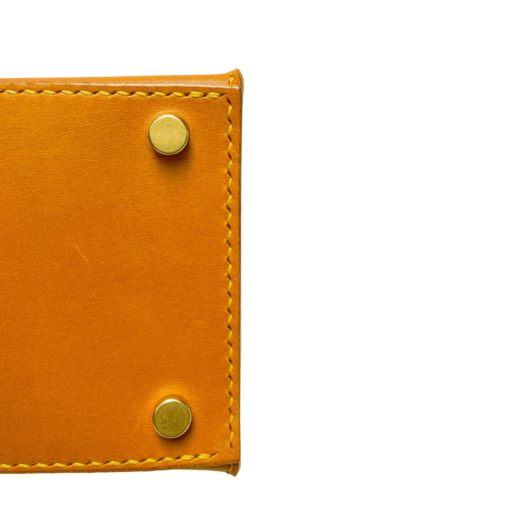 Close-up of a yellow leather wallet with gold rivets on a white background