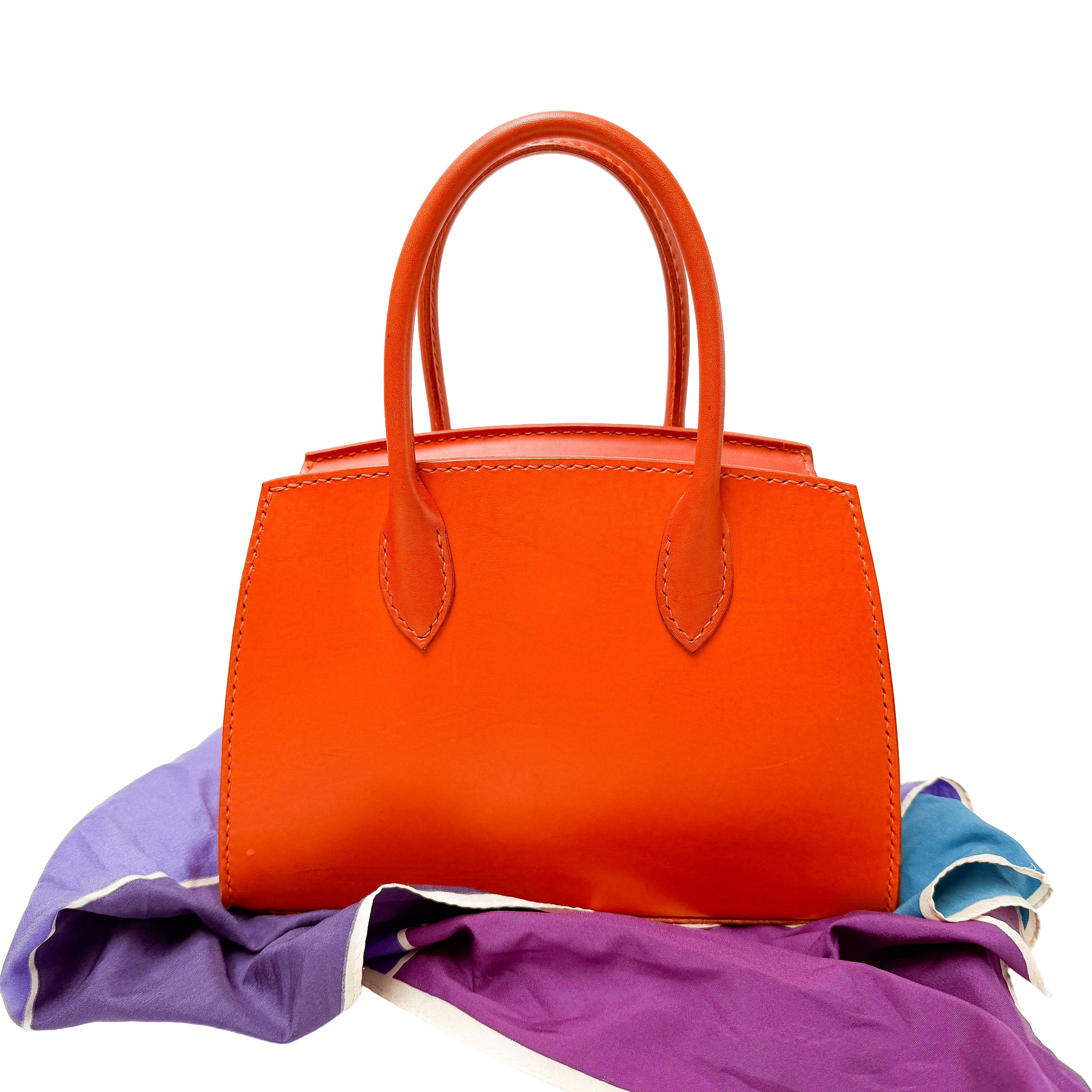 Orange handbag on a colorful fabric background