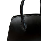 Close-up of a black leather handbag with handle on a white background