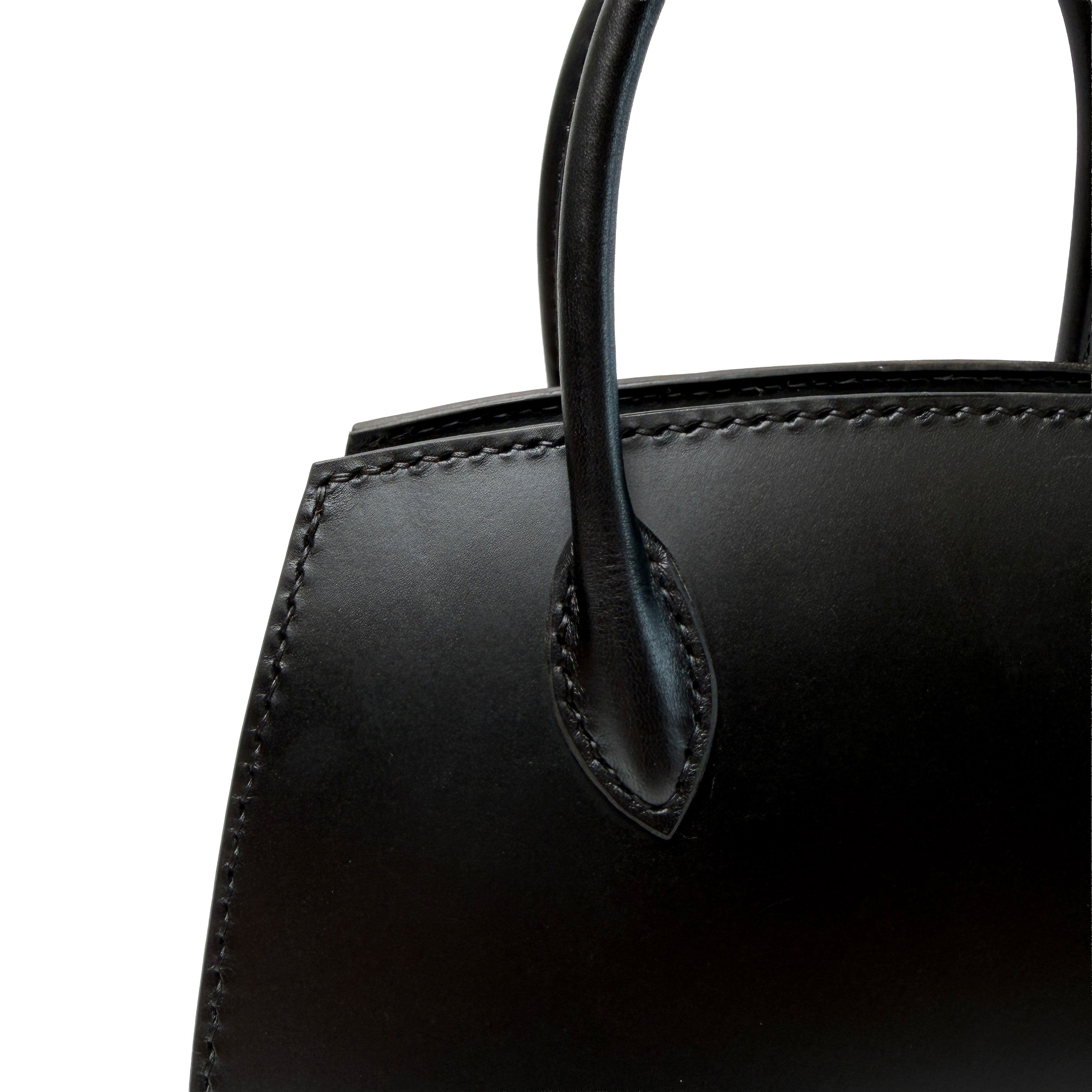 Close-up of a black leather handbag with handle on a white background