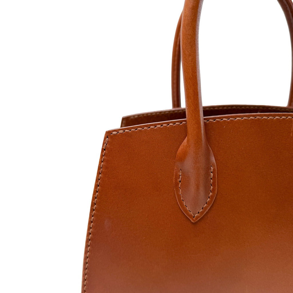 Brown leather handbag with handle on a white background