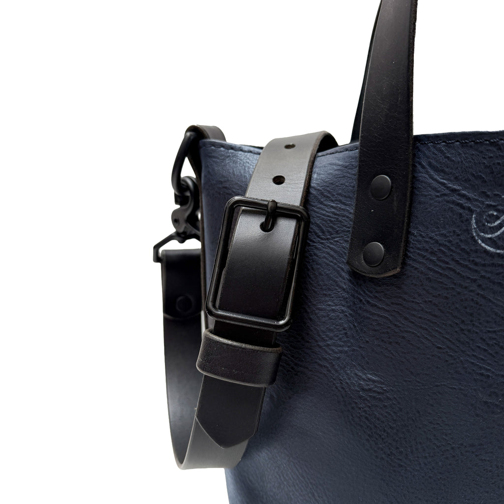 Navy leather bag with black strap and buckle on a white background