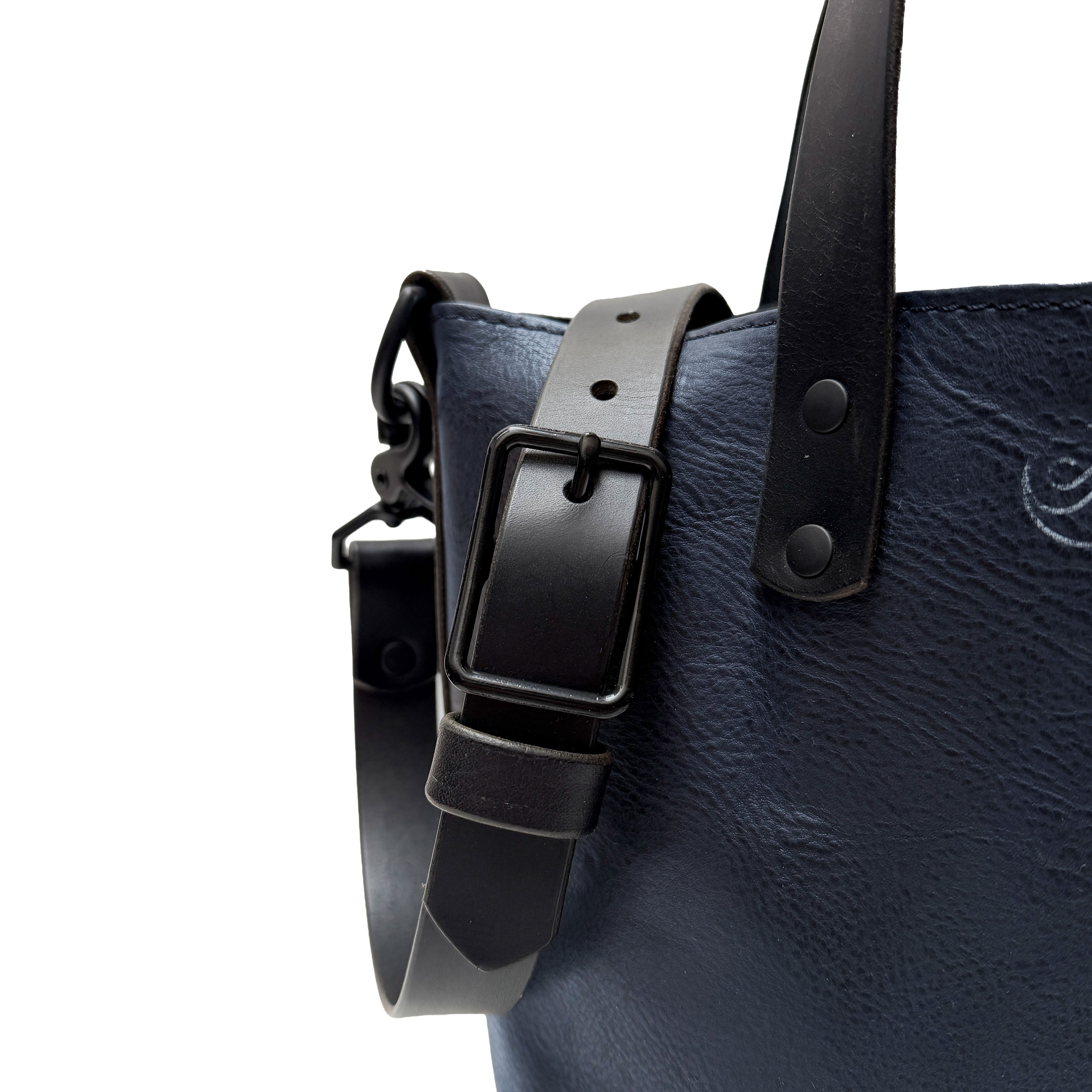 Navy leather bag with black strap and buckle on a white background