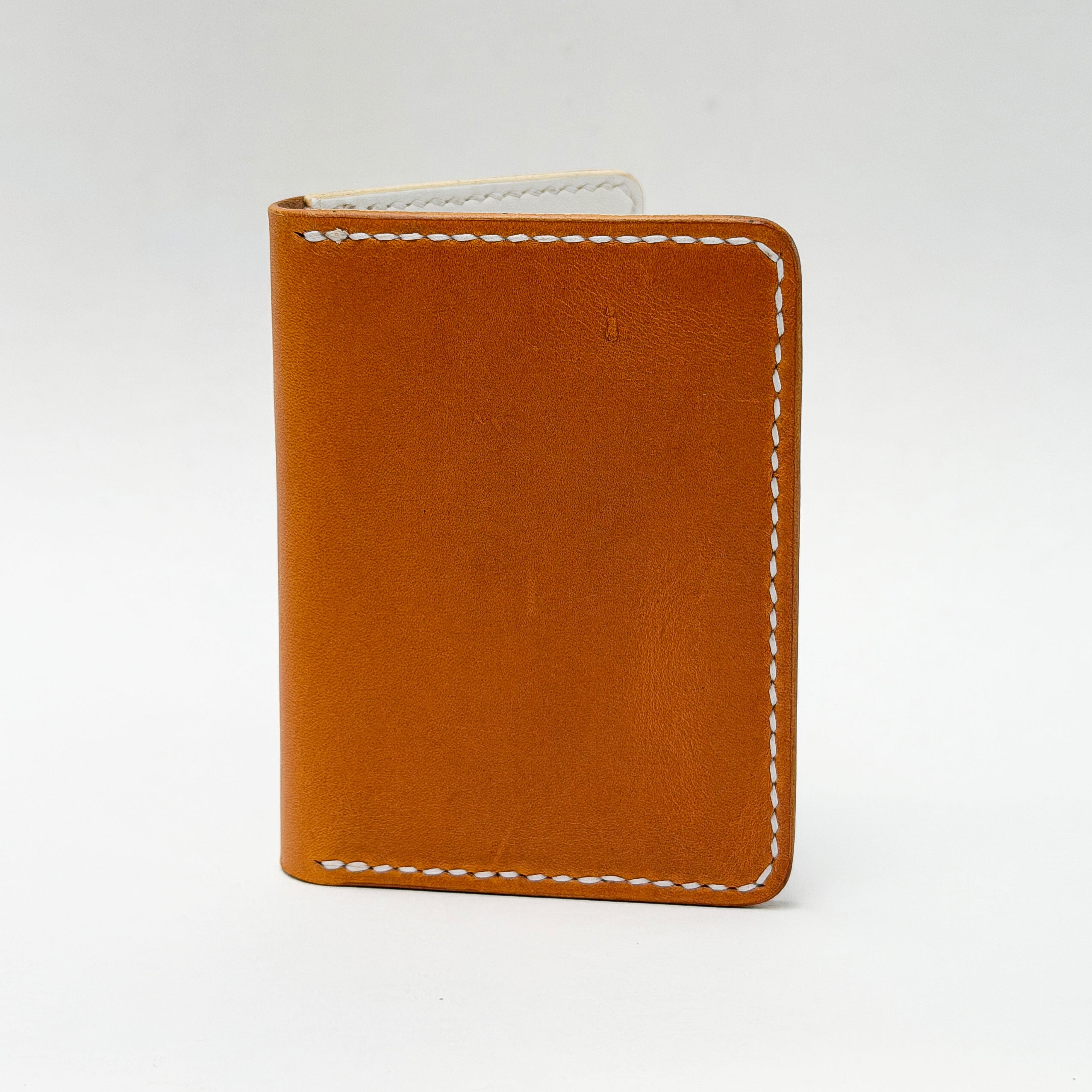 Yellow leather wallet with white stitching on a light gray background