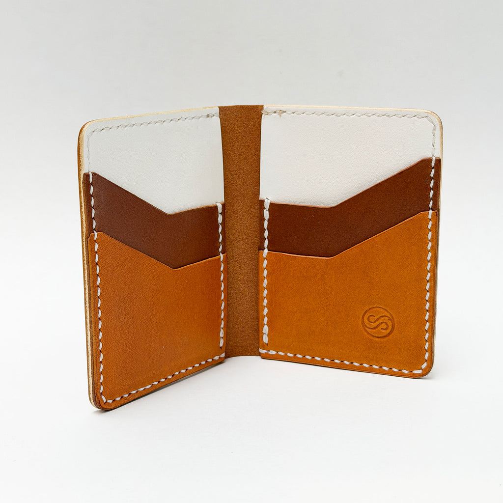 Open leather wallet with brown and white interior on a light gray background
