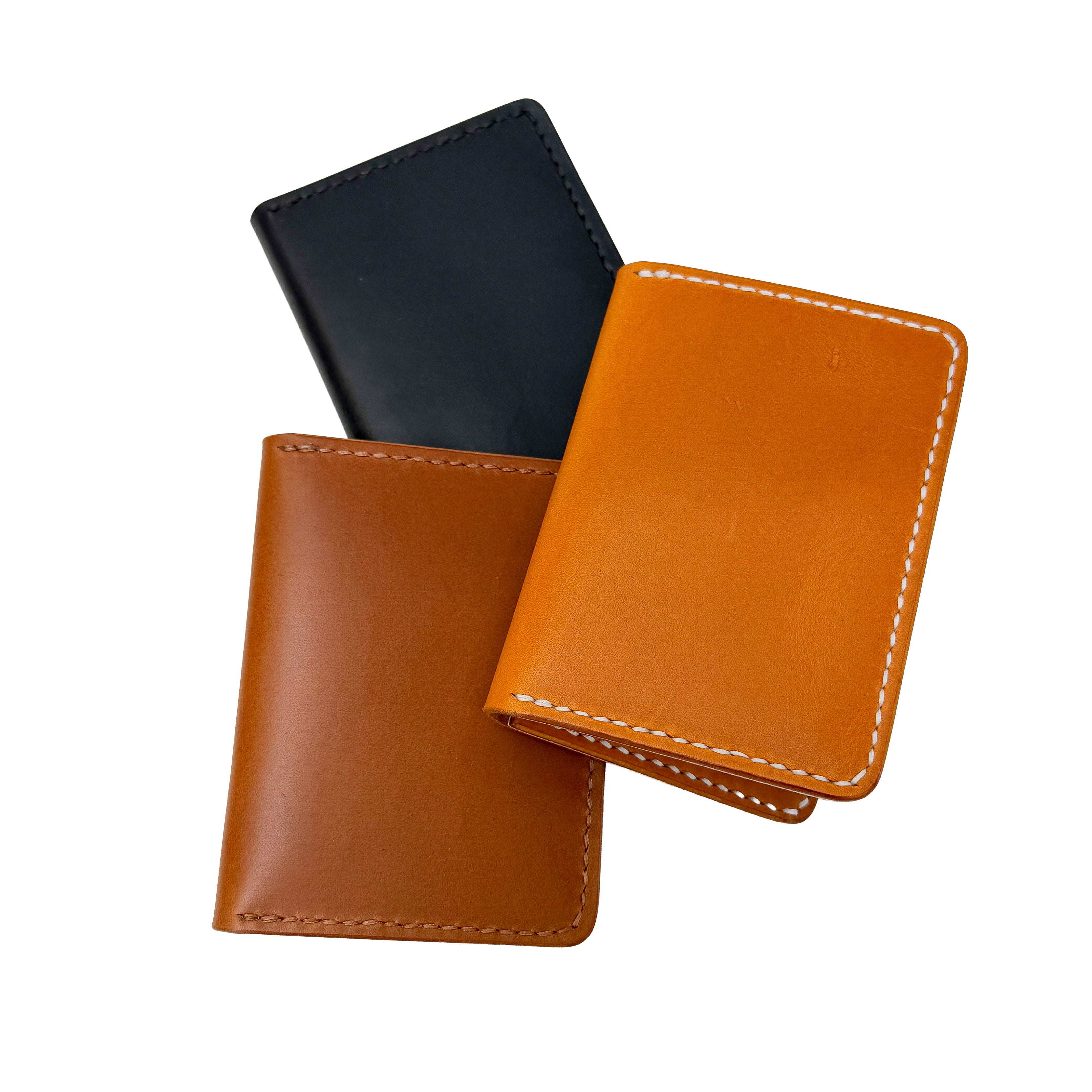 Three leather card holders in black, brown, and orange on a white background