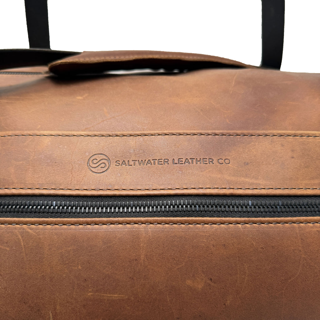 Brown leather duffle bag with Saltwater Leather logo on a white background