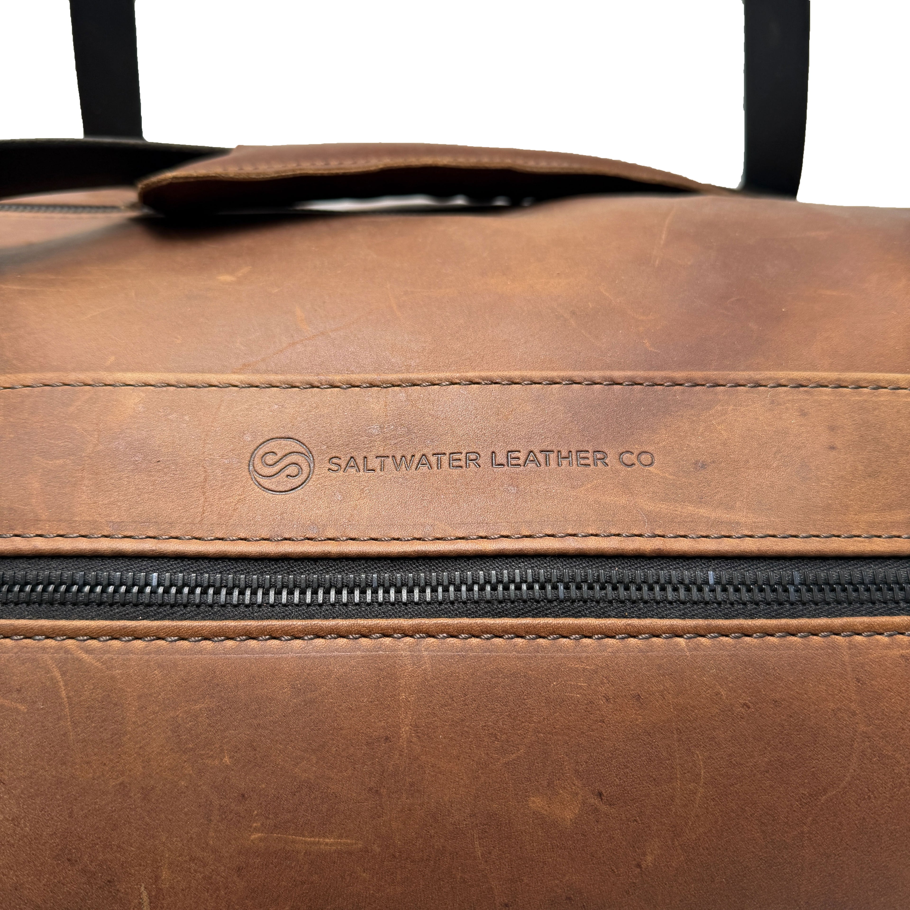 Brown leather duffle bag with Saltwater Leather logo on a white background