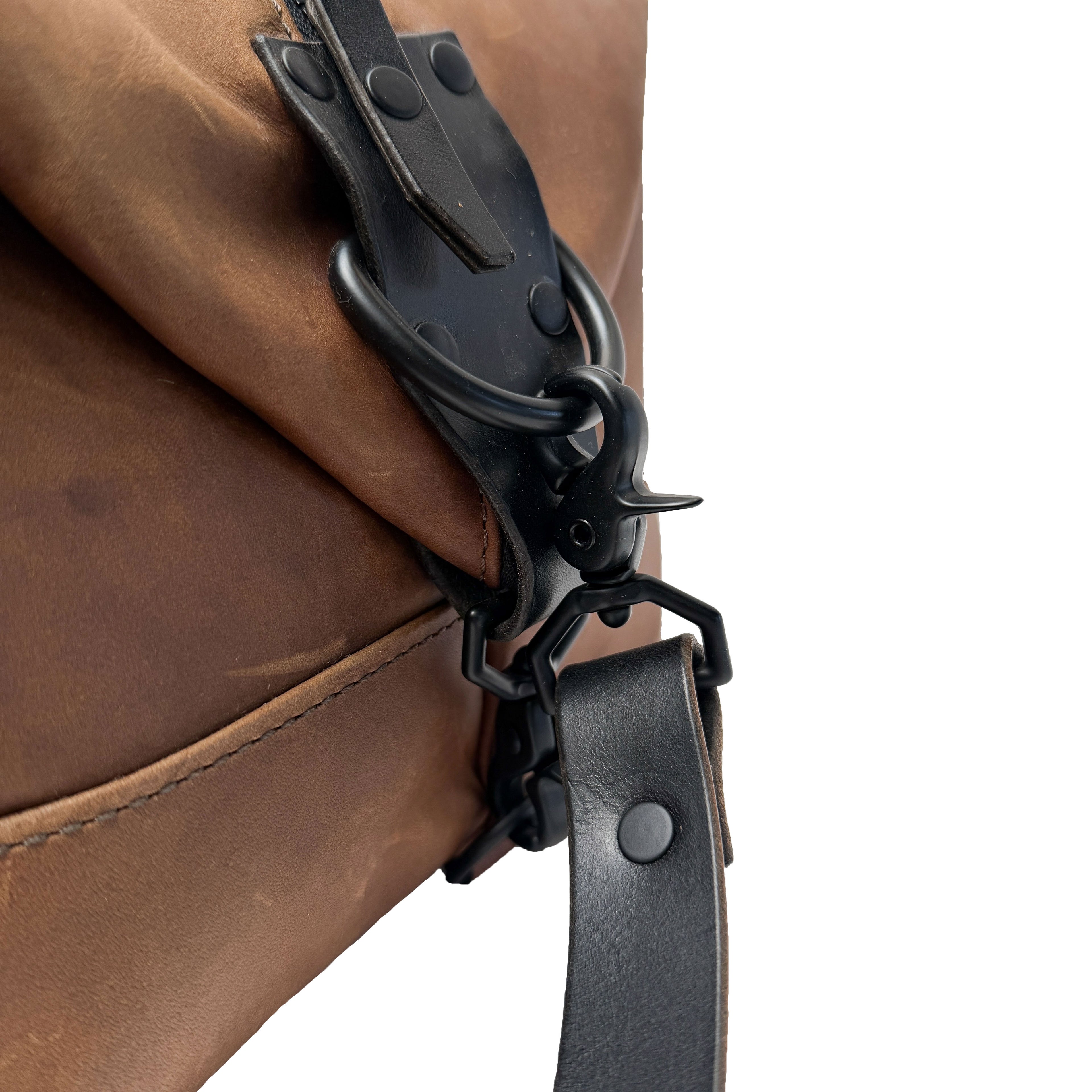 Close-up of a brown leather bag with a black strap and clasp on a white background