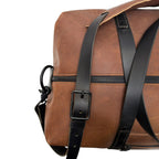 Brown leather duffle bag with black straps on a white background