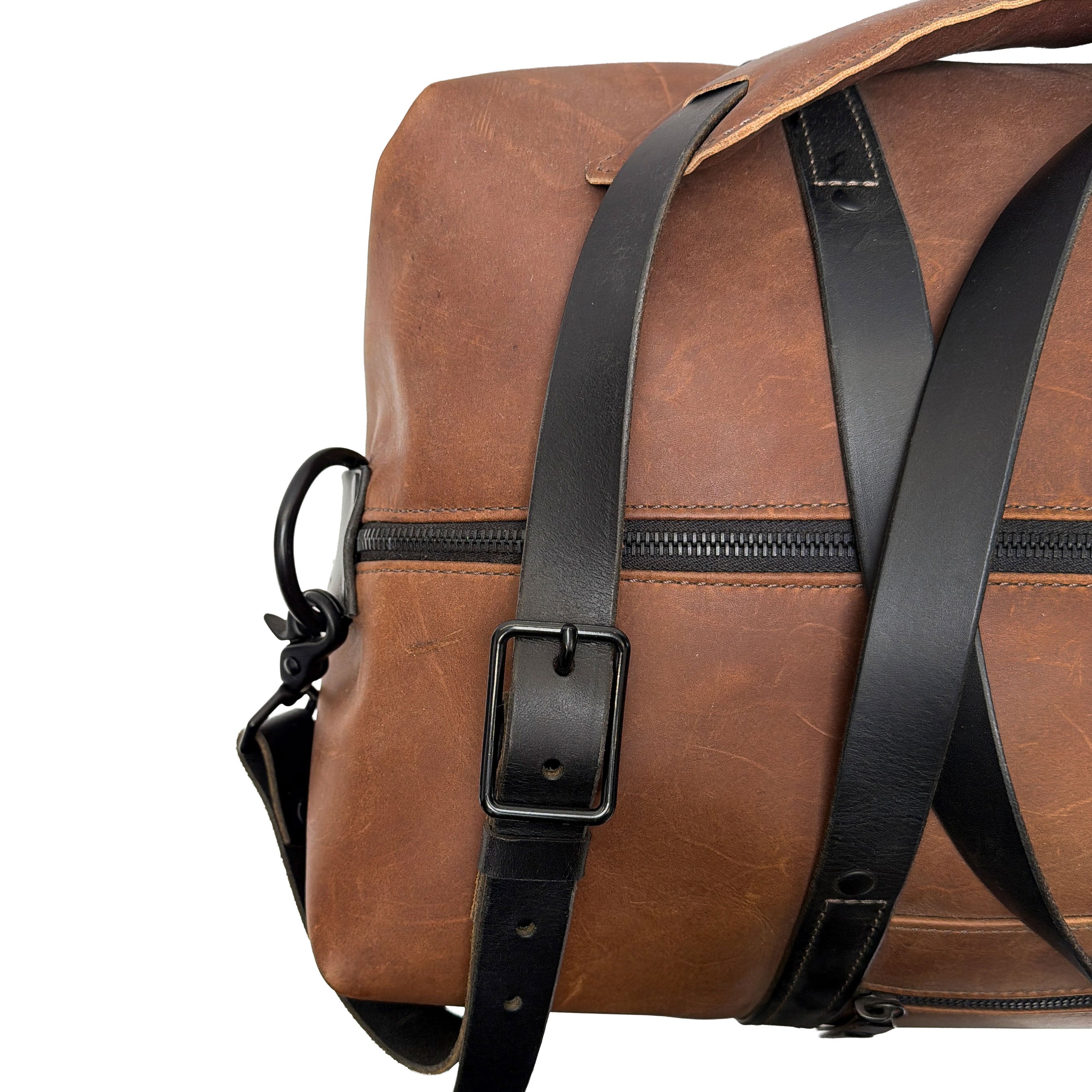 Brown leather duffle bag with black straps on a white background