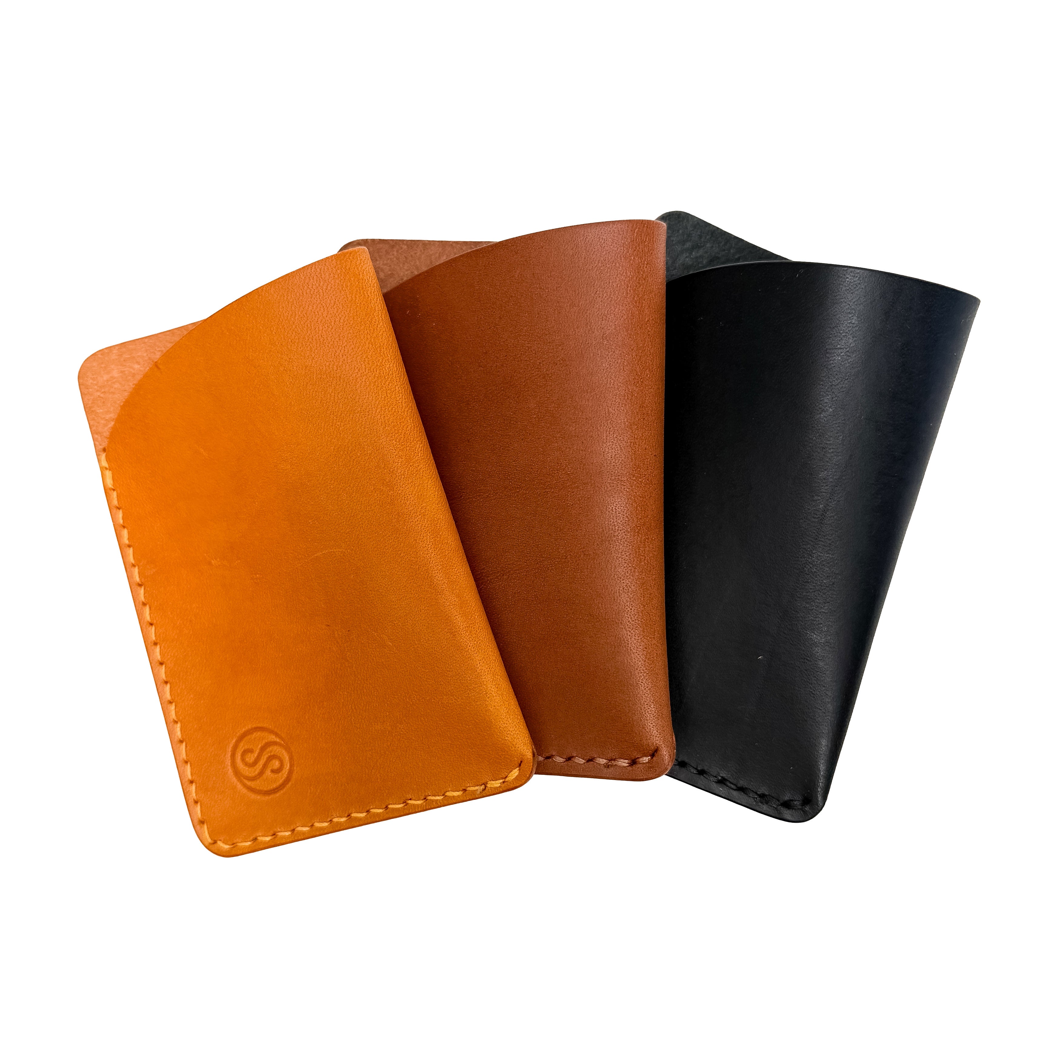 Three leather card holders in orange, brown, and black on a white background