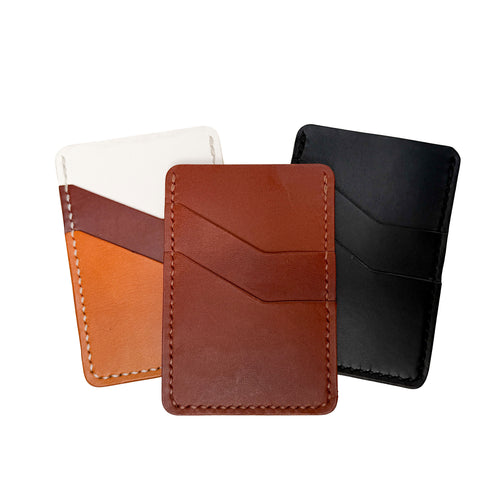 Three leather card holders in different colors on a white background