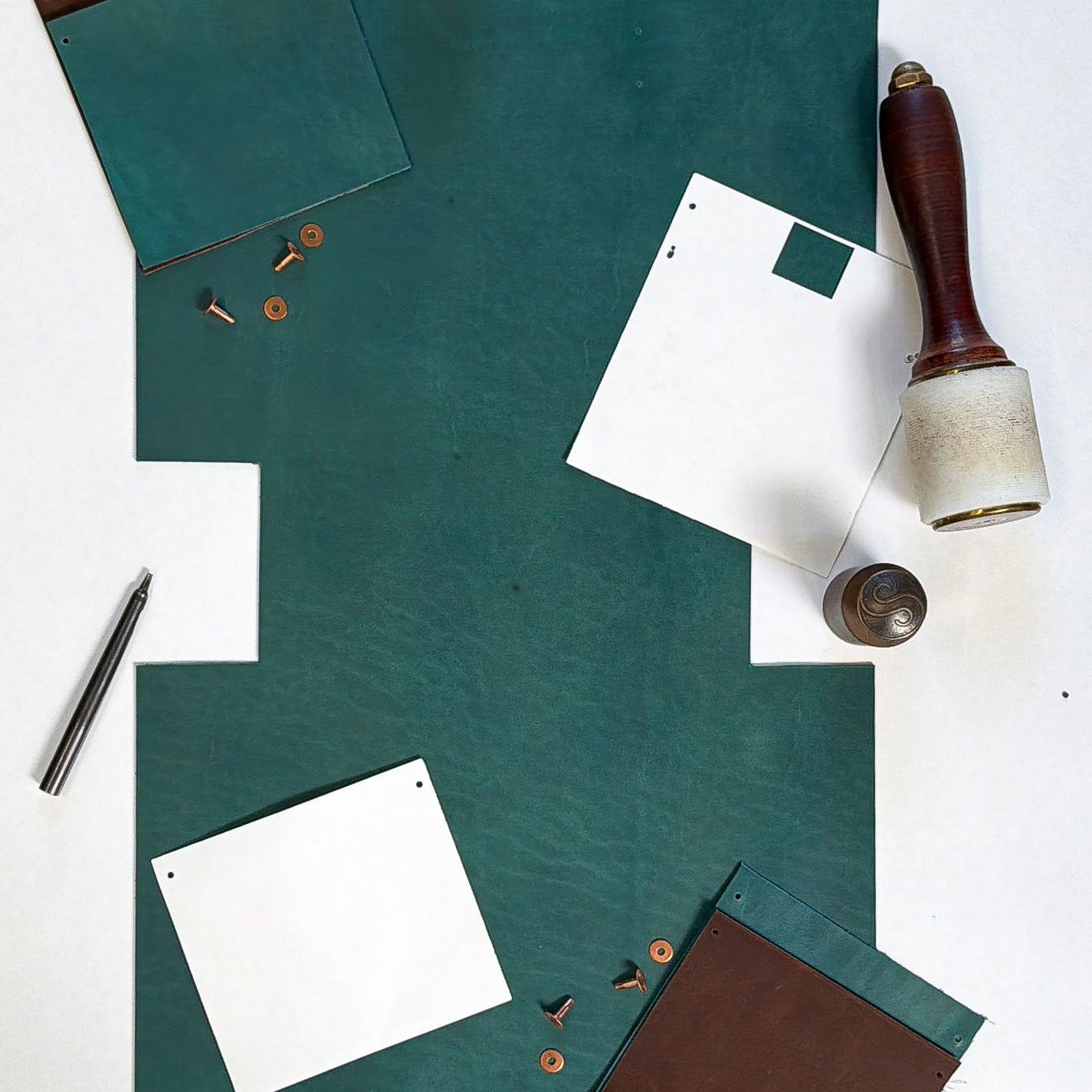 Green leather sheets, white paper, and a stamp on a white background