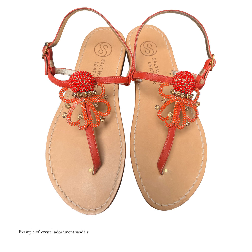 Pair of sandals with red crystal embellishments on a white background